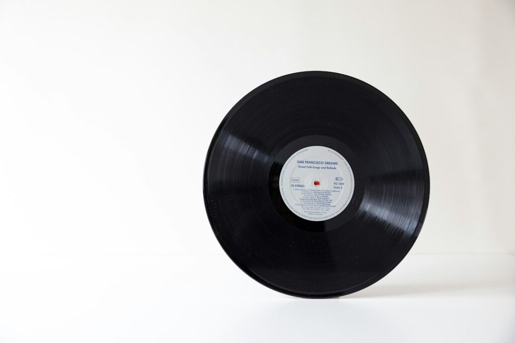 A black vinyl record with a central label on a white surface