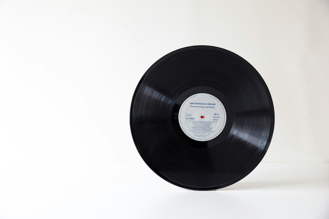 A black vinyl record with a central label on a white surface
